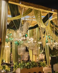 a room filled with lots of chandeliers hanging from the ceiling and green drapes