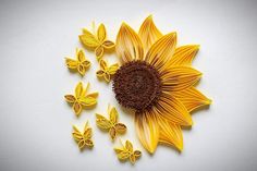 a sunflower made out of yellow paper with butterflies around it on a white surface