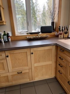 a kitchen with wooden cabinets and counter tops next to a large window overlooking the woods