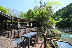 a wooden deck with tables and chairs next to a river