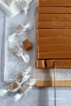 some pieces of chocolate sitting on top of wax paper next to a cutting board and knife