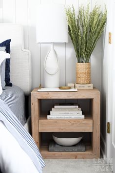 a nightstand with books and a vase on it