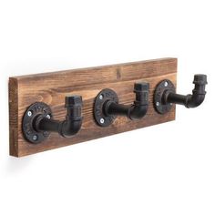 a wooden wall mounted with three black pipe holders and two metal fittings on each side