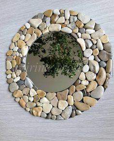 a mirror made out of rocks with a tree in the middle and leaves on it