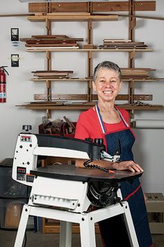 a woman is standing in front of a table with a sewing machine on it and shelves behind her