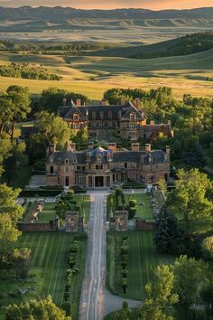 an aerial view of a large mansion in the middle of a lush green field with trees