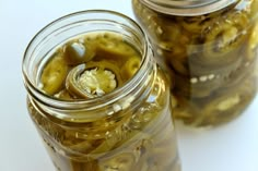 two jars filled with pickles sitting next to each other