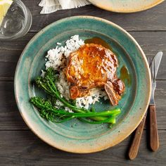 two plates with chicken, rice and broccoli on them next to utensils