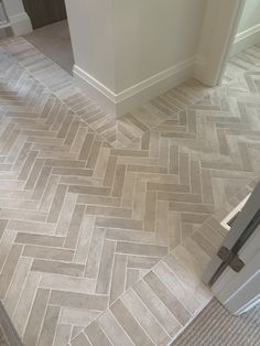 a bathroom with herring tile flooring next to a door and toilet paper dispenser