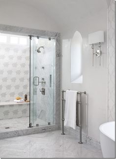 a white bathroom with a glass shower door and standup shower in the corner next to a bathtub