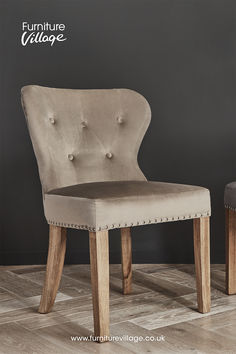 an upholstered chair with buttons on the back and seat, in front of a gray wall