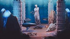 an underwater scene with statues and fish in the water, surrounded by other sea creatures