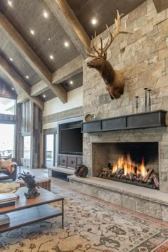 a living room with a fire place, couches and a deer head mounted on the wall