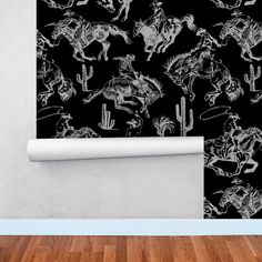 the wallpaper is decorated with black and white drawings of horses, cowboys, and cacti