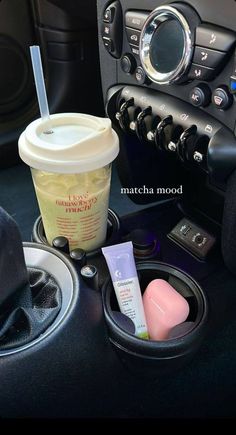 the cup is sitting on the dash board next to the steering wheel and other items