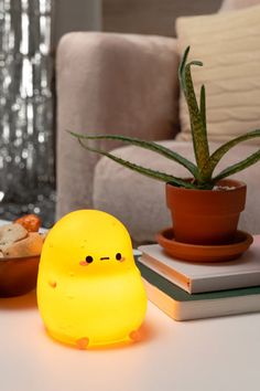 a yellow light sitting on top of a white table next to a potted plant