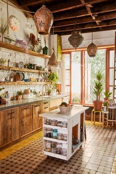 a kitchen with lots of pots and pans hanging from the ceiling, next to a tiled floor