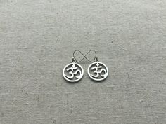 "Stunning silver Ohm round earrings. These are the perfect accessory for any yoga, meditation lover. Bring a little namaste into your life. Made from allergy free plated silver. They measure 5/8\" across by 3/4\" long and hang from simple silver ear wire hooks. I have a matching necklace in my Etsy shop. Here is the link https://etsy.me/2VBdAv9 Thanks for stopping by! Please take a moment and visit the rest of my Etsy shop. I have many more unique and stylish jewelry to choose from. 🌸 Tiger Flo Silver Symbolic Hypoallergenic Earrings, Silver Hypoallergenic Symbolic Earrings, Symbolic Round Earrings For Pierced Ears, Pierced Symbolic Round Earrings, Symbolic Round Pierced Earrings, Nickel-free Symbolic Round Earrings, Symbolic Nickel-free Round Earrings, Symbolic Round Nickel-free Earrings, Ohm Jewelry