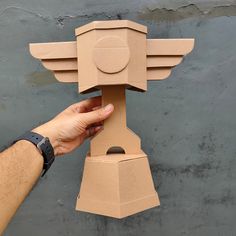 a hand is holding an object made out of cardboard with wings on it's head