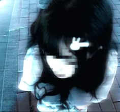 a blurry image of a woman sitting on the ground with her head in her hands