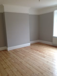 an empty room with hard wood floors and gray walls