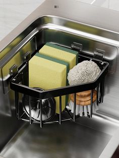 two sponges and scrub pads in a stainless steel dishwasher basket on top of a sink