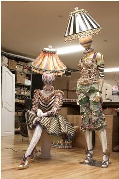 two mannequins are sitting next to each other in front of a lamp