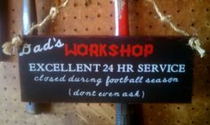 a sign hanging on the wall that says dad's workshop excellent 24 hour service closed during football season don't even ask