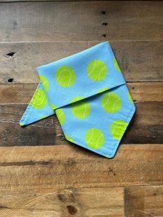 a blue napkin with green tennis balls on it sitting on top of a wooden floor