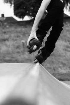 a skateboarder in black and white is doing a trick on the edge of a ramp