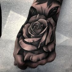 a black and white rose tattoo on the left hand