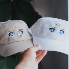 two hats with eyes painted on them are being held up by someone's hand