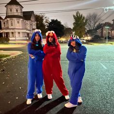 three girls in blue and red onesuits are standing on the street at night