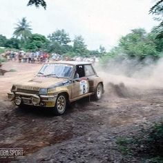 a dirt rally car driving down a muddy road