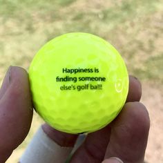 a person holding a yellow golf ball that says happiness is finding someone else's golf ball