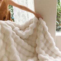 a woman is holding up a white blanket