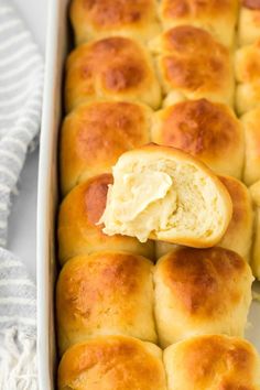 baked rolls in a baking dish with butter on top and one bite taken from the bread