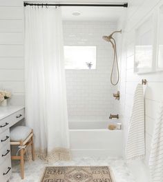 a white bathroom with a rug and shower curtain