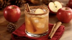 an apple cider with cinnamon sticks and apples in the background on a red napkin