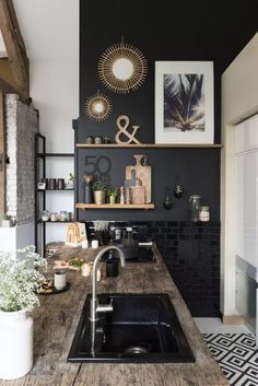 a kitchen with black walls and wooden counter tops, an open shelving above the sink