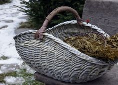 a wicker basket sitting on top of a wooden bench next to snow covered ground