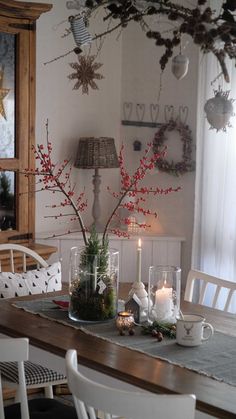 a dining room table set for christmas with candles and flowers in vases on it