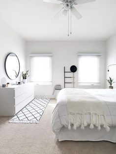 a bedroom with white walls and carpeted flooring has a ceiling fan in the corner