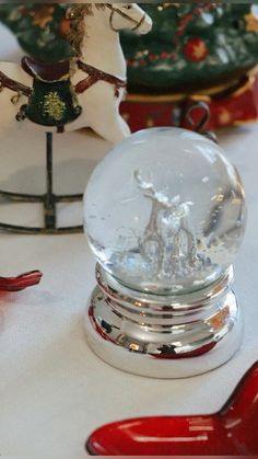 a snow globe sitting on top of a table next to red spoons and christmas decorations