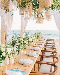 a long table with white flowers and greenery is set up for an outdoor dinner