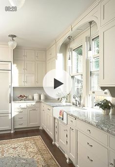 a kitchen with white cabinets and marble counter tops