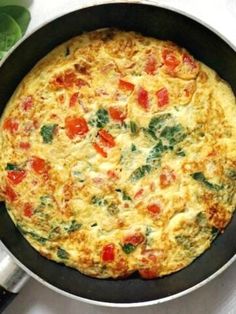 an omelet with tomatoes and spinach is in a pan on the table