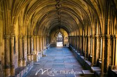 an arched hallway with stone pillars and benches on either side, leading into the distance