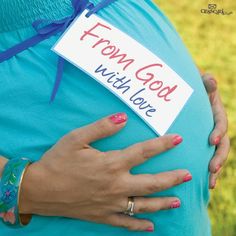 a pregnant woman's belly with a sign that says, from god we love you