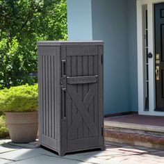 an outdoor storage box sitting on the side of a house next to a potted plant